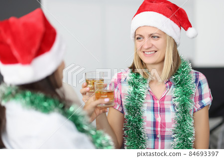 Happy women celebrate new year, drink alcoholic beverage, wearing festive hats 84693397