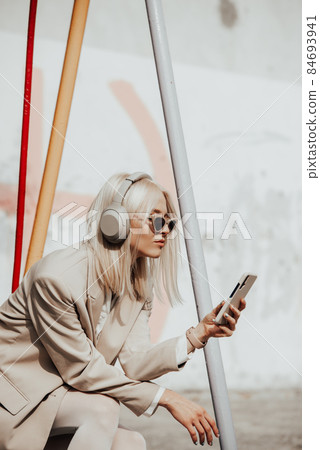 Portrait of blonde woman in headphones listening music with sunglasses. Hipster fashion model wear stylish wireless headphones enjoy listen new cool music. Portrait of blonde woman in headphones listening music with sunglasses. Hipster fashion model wear stylish wireless headphones enjoy listen new cool music. 84693941