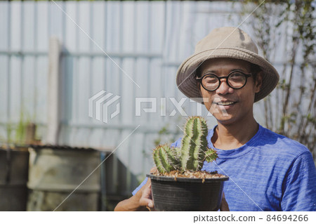 asian man holding pot of euphobia plant with happiness 84694266