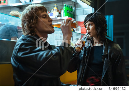 Couple of informal people drinking beverage from the bottle while standing Couple of informal people drinking beverage from the bottle while standing 84694482
