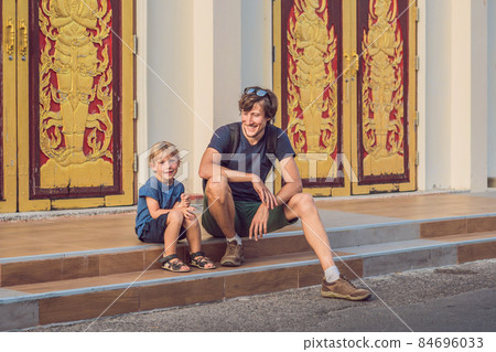 Father and son tourists in Thai temple in Phuket Town Wat Mongkolnimit Father and son tourists in Thai temple in Phuket Town Wat Mongkolnimit 84696033
