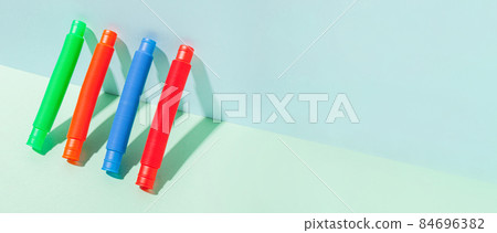 The straight folded pop tube stands leaning against the wall. Modern still life with antistress toy 84696382