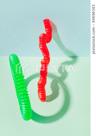 The curved pop tube stands leaning against the wall. Modern still life with antistress toy The curved pop tube stands leaning against the wall. Modern still life with antistress toy 84696383