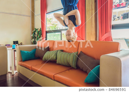 A woman stands upside down in the living room and meditates A woman stands upside down in the living room and meditates 84696591