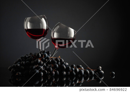 Glasses of red wine and blue grapes. Glasses of red wine and blue grapes. 84696922