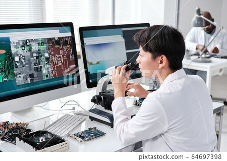 Young contemporary researcher with microscope Young contemporary researcher with microscope 84697398