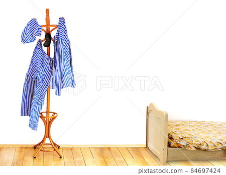 The striped pajamas hangs on the coat hook in an empty room with old bed. 84697424