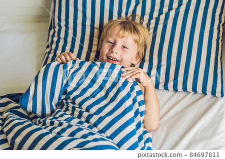 The cute boy woke up in his bed. Children sleep concept The cute boy woke up in his bed. Children sleep concept 84697811