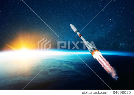 space rocket flies in the starry sky over the amazing blue planet earth and yellow sunset. Spaceship with blast flies into outer space. Travel to other planets concept. Successful start 84698030