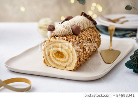 Buche de Noel. Traditional Christmas dessert, Christmas yule log cake with vanilla cream. Christmas tree branches. Buche de Noel. Traditional Christmas dessert, Christmas yule log cake with vanilla cream. Christmas tree branches. 84698341