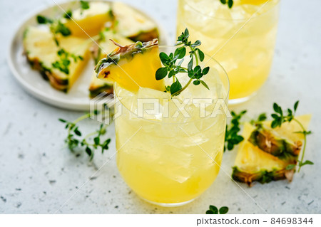 Pineapple cocktail with pulp in a glass and thyme. Pineapple cocktail with pulp in a glass and thyme. 84698344