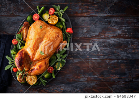 Festive celebration chicken with herbs for Thanksgiving or Christmas on wooden background. Festive celebration chicken with herbs for Thanksgiving or Christmas on wooden background. 84698347