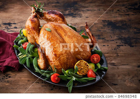 Festive celebration chicken with herbs for Thanksgiving or Christmas on wooden background. 84698348