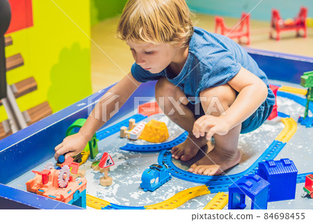 A boy is playing with a toy railroad A boy is playing with a toy railroad 84698455