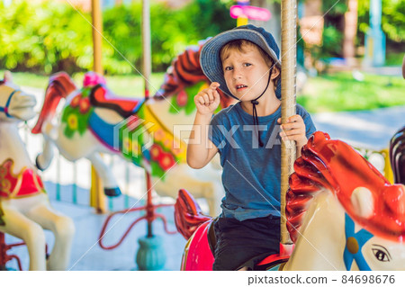 Cute little boy enjoying in funfair and riding on colorful carousel house Cute little boy enjoying in funfair and riding on colorful carousel house 84698676