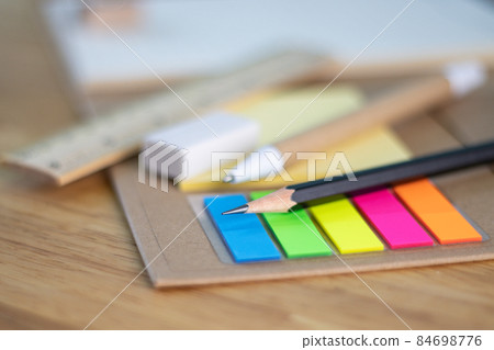 selective focus pencil for writing and multicolored square colorful sticky notes, rulers, and paper book on wood table concept equipment office and school 84698776