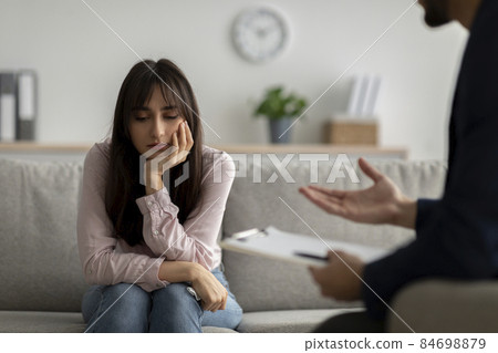 Unhappy young arab lady suffering from depression, listening psychologist advices, sitting in doctors office, copy space 84698879