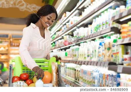 Black Woman Doing Shopping Putting Milk In Cart In Supermarket 84698909