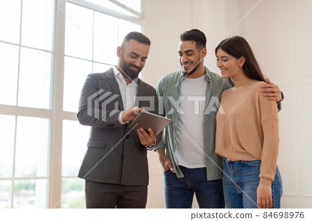 Couple Buying New Apartment, House Agent Showing Tablet Couple Buying New Apartment, House Agent Showing Tablet 84698976