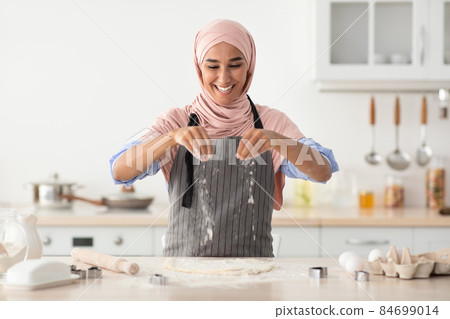 Islamic Lady In Hijab Baking In Kitchen, Sprinkle Flour On Rolled Dough 84699014