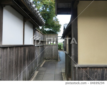 日本老房子之間的狹窄小巷,人們幾乎不能互相通過的鵝卵石小巷,木屋,粉刷的牆壁,瓦片屋頂 日本老房子之間的狹窄小巷,人們幾乎不能互相通過的鵝卵石小巷,木屋,粉刷的牆壁,瓦片屋頂 84699294