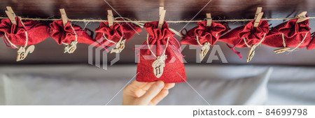Woman making Christmas advent calendar. Pouches on a rope BANNER, LONG FORMAT 84699798