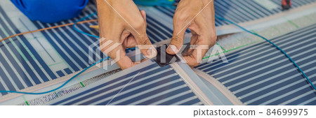 Master installs film warm floor in the room. Floor heating installation BANNER, LONG FORMAT Master installs film warm floor in the room. Floor heating installation BANNER, LONG FORMAT 84699975