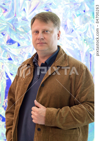 Portrait of an adult blond man in a corduroy jacket on the background of an abstract blue wall Portrait of an adult blond man in a corduroy jacket on the background of an abstract blue wall 84700263