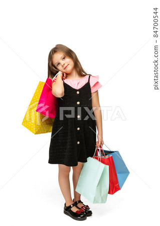 Studio shot of pretty little cute kid standing with multi colored shopping packages isolated over white background. Studio shot of pretty little cute kid standing with multi colored shopping packages isolated over white background. 84700544
