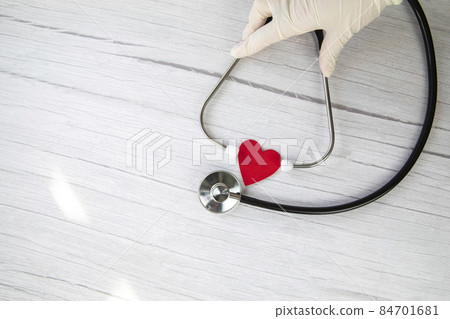 Red heart and white protective medical gloves holds a stethoscope on a white wooden background. Concept visit to the doctor, virus, treatment, diagnosis. Banner. Flat lay, top view copy space 84701681