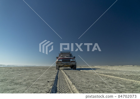 offroad car on pacific ocean sandy beach 84702073