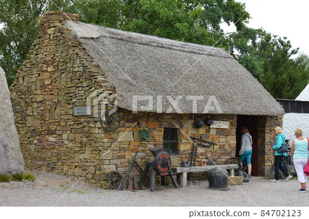 County Kerry, Republic of Ireland, August 15th 2019: A traditional 19th Century thatched Cottage at the Kerry Bog Village Museum in County Kerry, Republic of Ireland. County Kerry, Republic of Ireland, August 15th 2019: A traditional 19th Century thatched Cottage at the Kerry Bog Village Museum in County Kerry, Republic of Ireland. 84702123