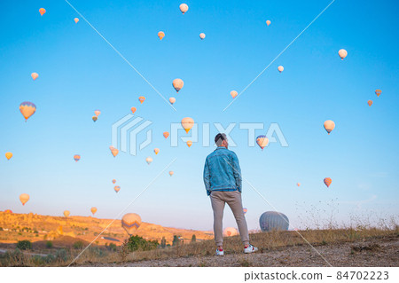 Happy man during sunrise watching hot air balloons in Cappadocia, Turkey Happy man during sunrise watching hot air balloons in Cappadocia, Turkey 84702223
