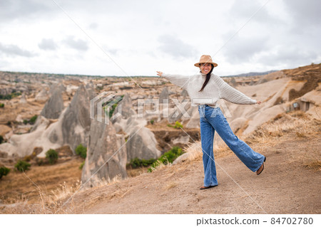 Young woman on the edge of canyon in Cappodocia Young woman on the edge of canyon in Cappodocia 84702780