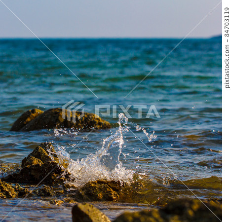 Waves hitting round rocks and splashing Waves hitting round rocks and splashing 84703119