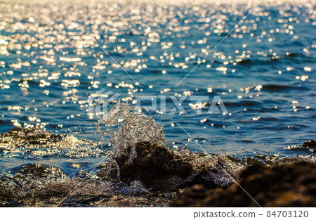 Waves hitting round rocks and splashing Waves hitting round rocks and splashing 84703120