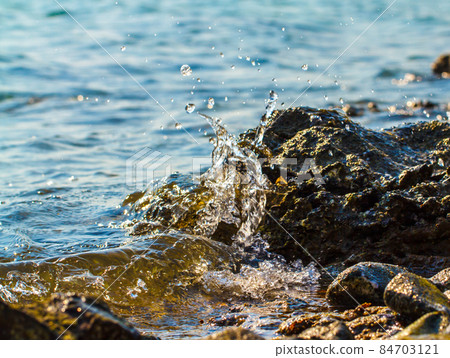 Waves hitting round rocks and splashing Waves hitting round rocks and splashing 84703121