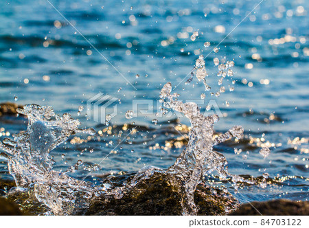 Waves hitting round rocks and splashing Waves hitting round rocks and splashing 84703122