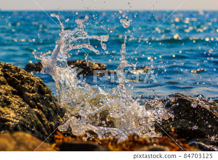 Waves hitting round rocks and splashing Waves hitting round rocks and splashing 84703125