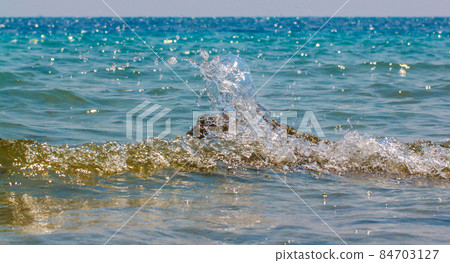 Waves hitting round rocks and splashing Waves hitting round rocks and splashing 84703127