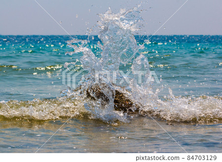 Waves hitting round rocks and splashing 84703129