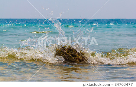 Waves hitting round rocks and splashing Waves hitting round rocks and splashing 84703477