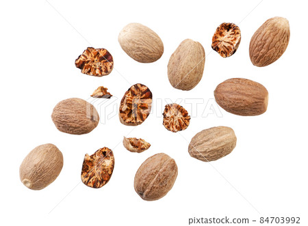 Nutmeg whole and pieces are falling on a white background, cut. Isolated 84703992