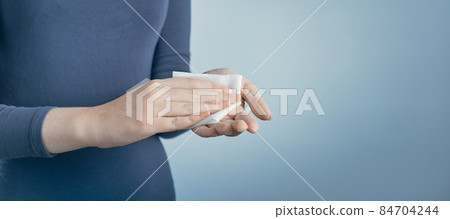 Girl cleaning her hands by using white antibacterial napkin on gray background. Photo with copy space. Girl cleaning her hands by using white antibacterial napkin on gray background. Photo with copy space. 84704244