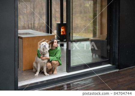 Young woman with her dog at modern house on nature Young woman with her dog at modern house on nature 84704744