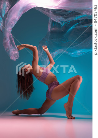 One young flexible contemp dancer dancing with fabric isolated on gradient blue white background in neon light One young flexible contemp dancer dancing with fabric isolated on gradient blue white background in neon light 84705462