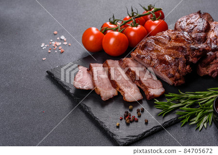 grilled beef steaks with spices on a dark cutting board grilled beef steaks with spices on a dark cutting board 84705672