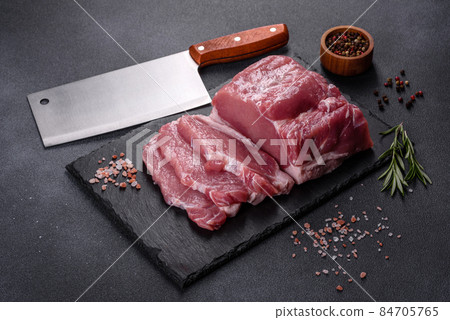 Raw pork steak on a cutting board with herbs and spices 84705765