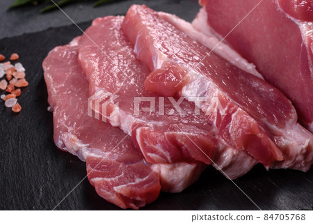 Raw pork steak on a cutting board with herbs and spices 84705768