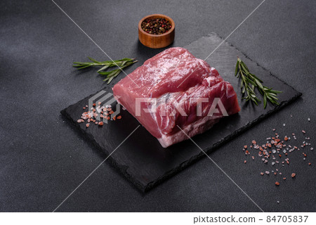 Raw pork steak on a cutting board with herbs and spices Raw pork steak on a cutting board with herbs and spices 84705837